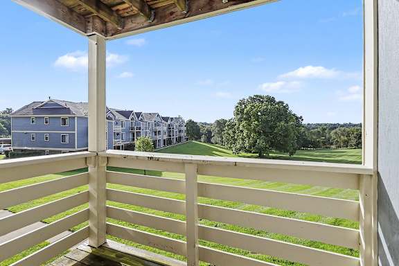 A balcony with a view of a green courtyard at Pine Knoll Apartments, Battle Creek