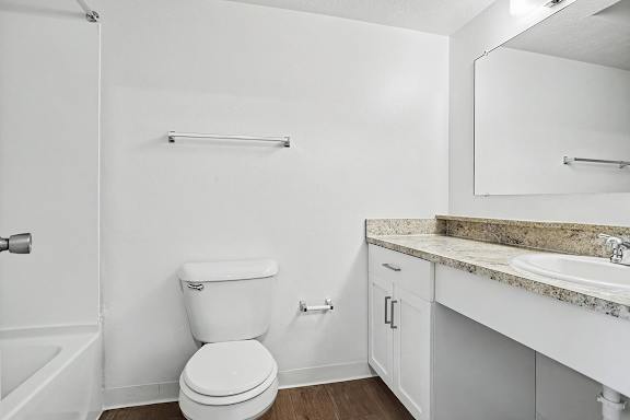 A white toilet sits in a bathroom next to a sink at Pine Knoll Apartments, Battle Creek
