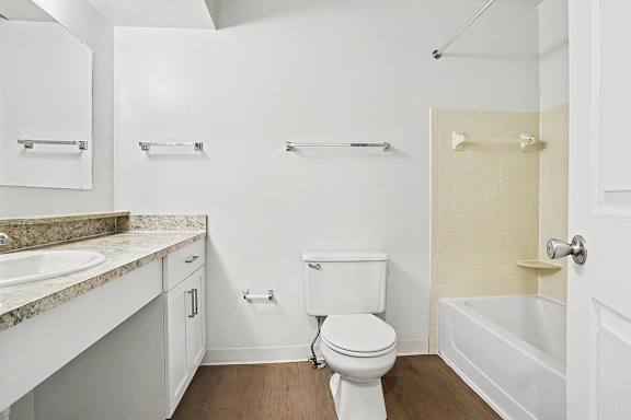A white bathroom with a toilet, sink, and bathtub at Pine Knoll Apartments, Battle Creek