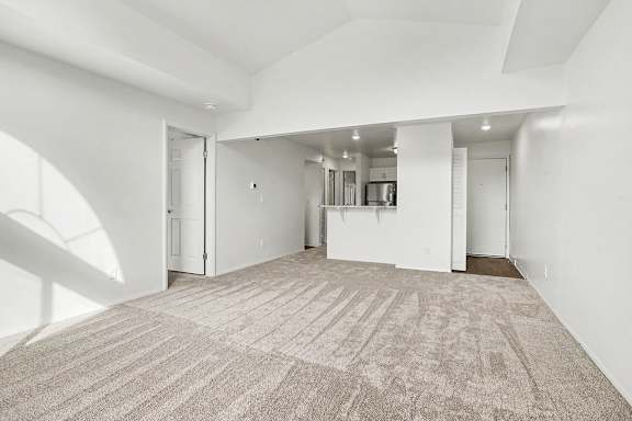 A large, empty dining room with a carpeted floor and white walls at Pine Knoll Apartments, Battle Creek