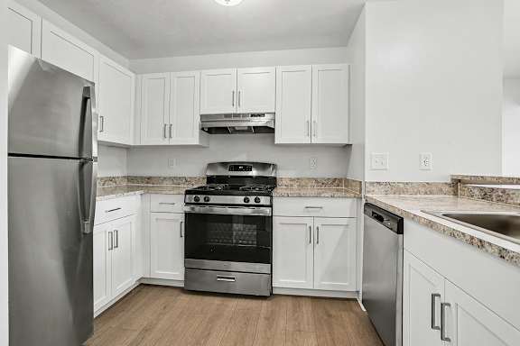 A kitchen with white cabinets and a stainless steel refrigerator at Pine Knoll Apartments, Battle Creek