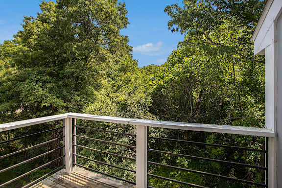A balcony with a metal railing overlooks a wooded area A balcony with a metal railing overlooks a wooded area at Pine Knoll Apartments, Battle Creek, 49014