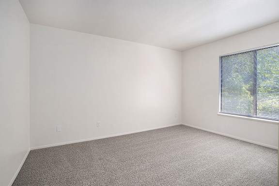 A bedroom with a carpeted floor and a window with blinds A bedroom with a carpeted floor and a window with blinds at Pine Knoll Apartments, Battle Creek, 49014