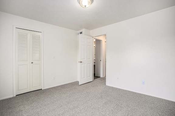 A bedroom with a walk-in closet and a carpeted floor A bedroom with a walk-in closet and a carpeted floor at Pine Knoll Apartments, Battle Creek, 49014