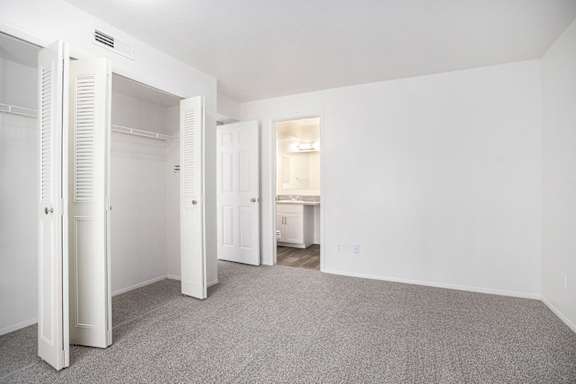 A bedroom with a large closet, grey carpet and an ensuite bathroom A bedroom with a large closet, grey carpet and an ensuite bathroom at Pine Knoll Apartments, Battle Creek, 49014