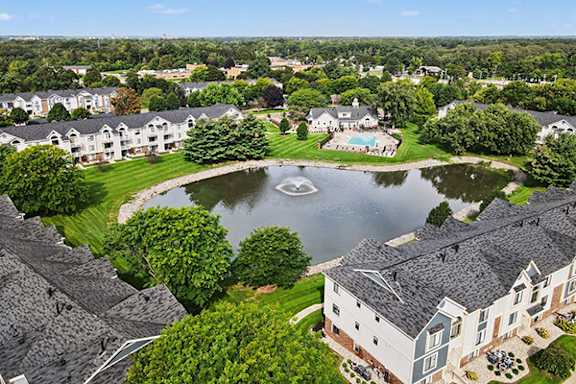 A bird's eye view of an apartment community with a pond at Pine Knoll Apartments in Battle Creek, MI