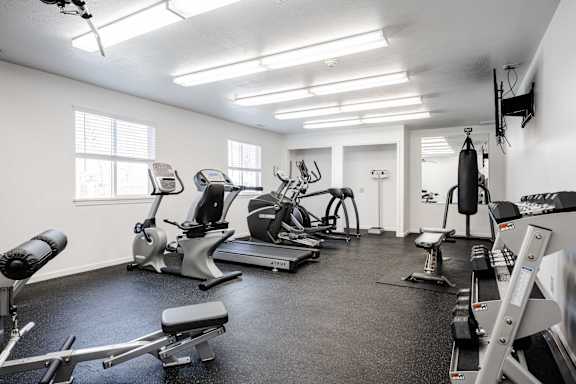 A spacious gym with a variety of equipment including treadmills, stationary bikes, and weight machines.