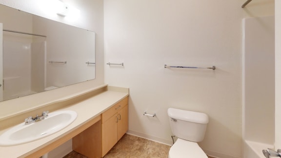 a bathroom with a toilet and a sink and a mirror  at Hunters Pond Apartment Homes, Champaign