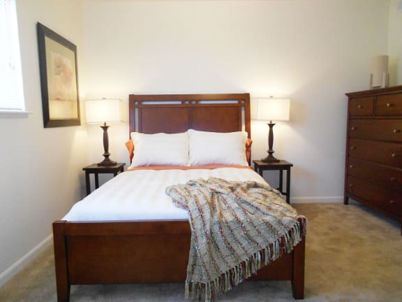 a bedroom with a bed and two lamps at Hunters Pond Apartment Homes, Champaign, Illinois