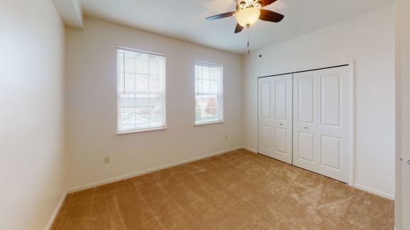an empty bedroom with a ceiling fan and two windows  at Hunters Pond Apartment Homes, Illinois, 61820