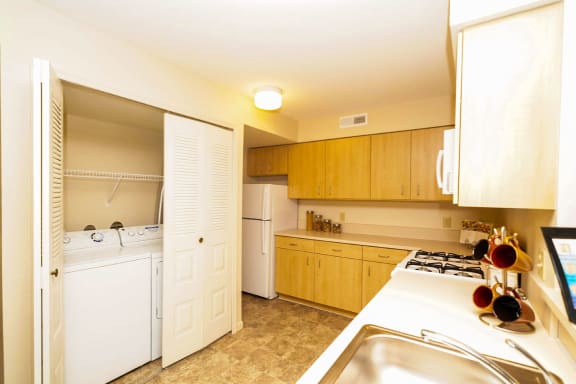 a kitchen with white appliances and wooden cabinets  at Hunters Pond Apartment Homes, Champaign