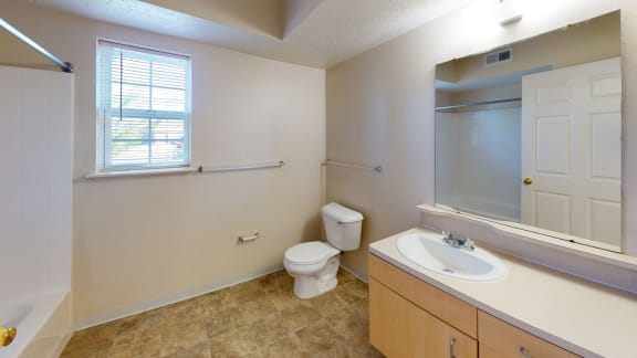 a bathroom with a toilet and a sink and a mirror  at Hunters Pond Apartment Homes, Champaign, 61820