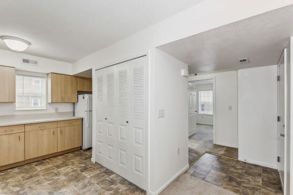 an empty kitchen with wooden cabinets and a white refrigerator at Hunters Pond Apartment Homes in Champaign, Illinois