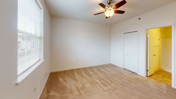 an empty living room with a ceiling fan and a door to a closet  at Hunters Pond Apartment Homes, Champaign, Illinois
