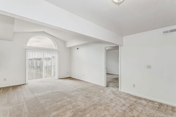 an empty living room with a large arched window and a door to a bedroom  at Hunters Pond Apartment Homes, Champaign, IL