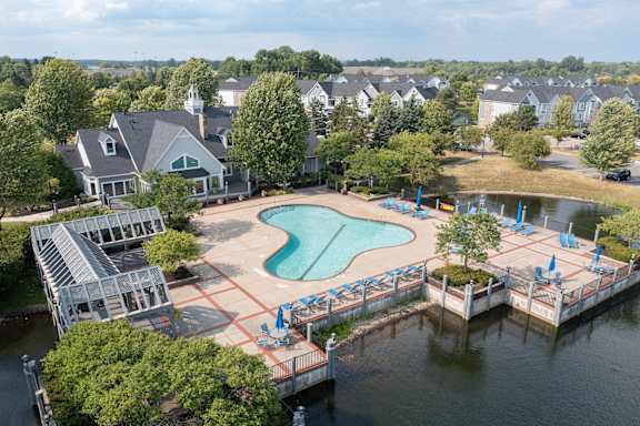 A large swimming pool with a deck and sun loungers is surrounded by houses.