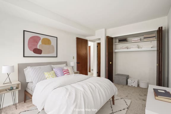 a bedroom with white walls and a white bed with colorful pillows at Sycamore Creek Apartments, Michigan