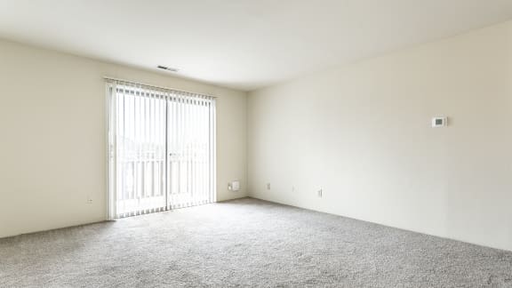 an empty living room with white walls and a sliding glass door in Indianapolis, IN