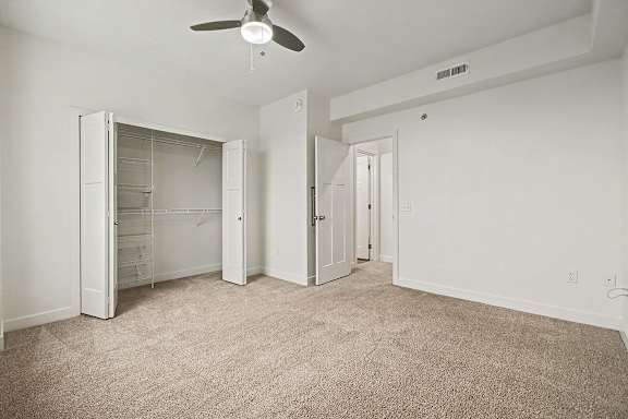A bedroom with a walk-in closet and ceiling fan at The Reserve at The Reserve at Destination Pointe in Grimes, IA 50111