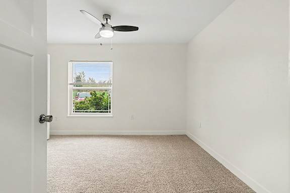 A bedroom with a carpet floor, a ceiling fan and window at The Reserve at The Reserve at Destination Pointe in Grimes, IA 50111