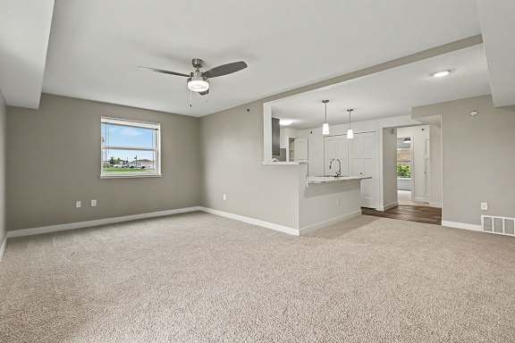 An enlarged living room with a ceiling fan and a large window at The Reserve at The Reserve at Destination Pointe in Grimes, IA 50111