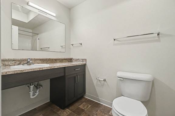 A bathroom with a toilet, sink, and mirror at The Reserve at The Reserve at Destination Pointe in Grimes, IA 50111