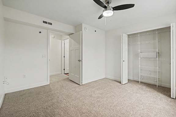 A bedroom with a ceiling fan and a walk-in closet with wardrobe organizers at The Reserve at The Reserve at Destination Pointe in Grimes, IA 50111