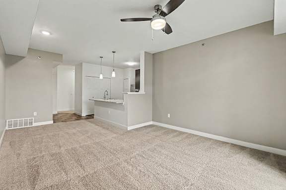 A spacious dining room with a carpeted floor and a ceiling fan at The Reserve at The Reserve at Destination Pointe in Grimes, IA 50111
