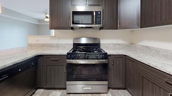 A modern kitchen with a stainless steel stove top oven and microwave at The Reserve at Destination Pointe apartments, Grimes, IA