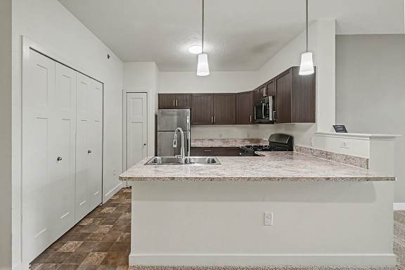 A kitchen with a breakfast bar and stainless steel appliances at The Reserve at The Reserve at Destination Pointe in Grimes, IA 50111