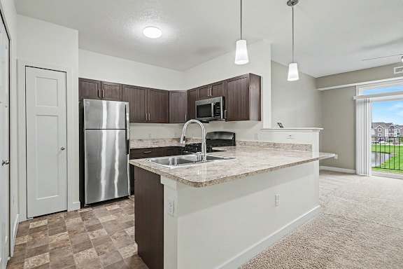A kitchen with a pantry, refrigerator, microwave, oven and dishwasher at The Reserve at The Reserve at Destination Pointe in Grimes, IA 50111