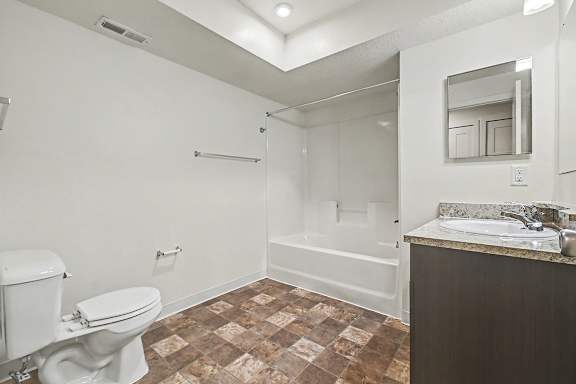 A bathroom with a toilet, sink, and bathtub at The Reserve at The Reserve at Destination Pointe in Grimes, IA 50111