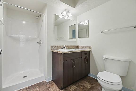 A bathroom with a shower, toilet, sink, and mirror at The Reserve at The Reserve at Destination Pointe in Grimes, IA 50111
