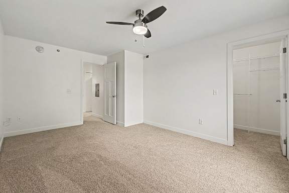 A bedroom with a ceiling fan and a large walk-in closet with organizers at The Reserve at The Reserve at Destination Pointe in Grimes, IA 50111