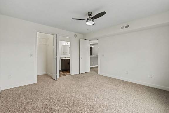 A bedroom with a ceiling fan, walk-in closet, and ensuite bathroom at The Reserve at The Reserve at Destination Pointe in Grimes, IA 50111