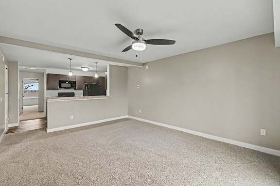 A spacious living and dining room with a ceiling fan and carpeted floor at The Reserve at The Reserve at Destination Pointe in Grimes, IA 50111