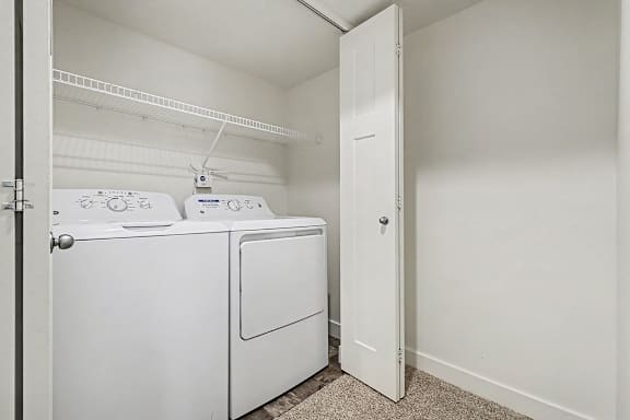 A full-size washer and dryer in a small laundry room at The Reserve at The Reserve at Destination Pointe in Grimes, IA 50111