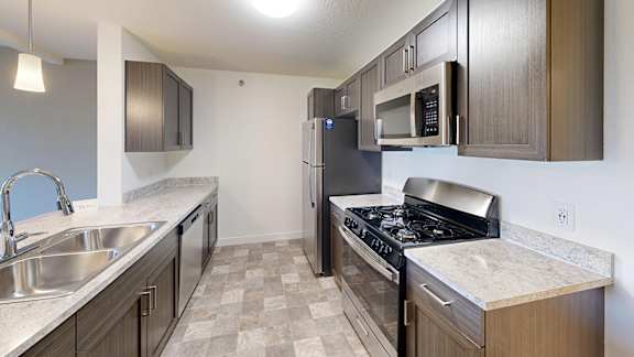 A kitchen with a stove top oven, microwave and dishwasher at The Reserve at Destination Pointe apartments, Grimes, IA.