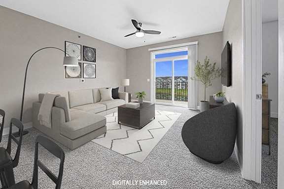 A living room with a 9' ceiling, grey sofa, armchair, and coffee table at The Reserve at Destination Pointe apartments, Grimes, IA