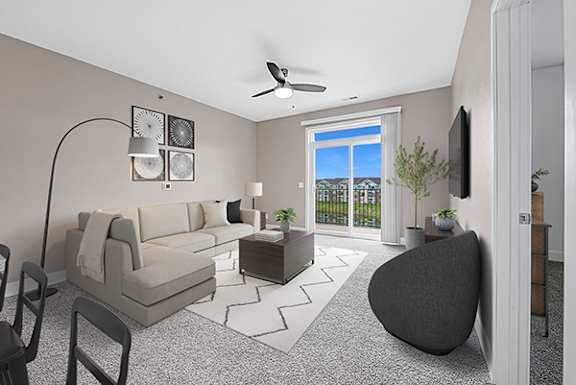 A living room with a 9' ceiling, grey sofa, armchair, and coffee table at The Reserve at Destination Pointe apartments, Grimes, IA
