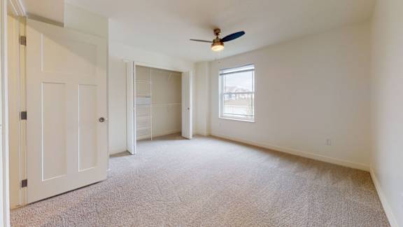A bedroom with a ceiling fan, window., and walk-in closet at The Reserve at Destination Pointe apartments, Grimes, IA