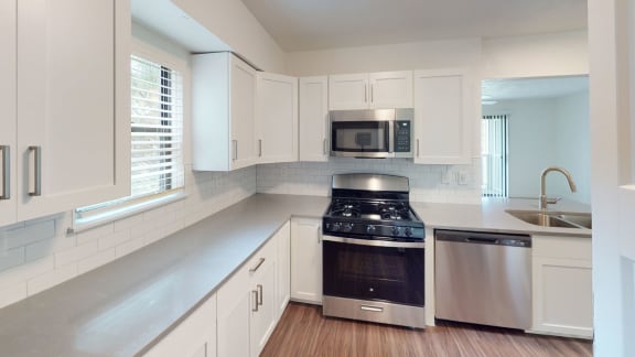 a kitchen with white cabinets and a stove and a microwave at Green Ridge Apartments, Grand Rapids, MI, 49544