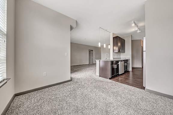 A spacious living room with a kitchen area in the background. at River Crossing Apartments, St. Charles, MO, 63303
