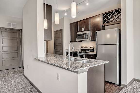A kitchen with a granite countertop and stainless steel appliances. at River Crossing Apartments, Missouri