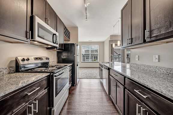A modern kitchen with dark wood cabinets and granite countertops. at River Crossing Apartments, St. Charles, MO