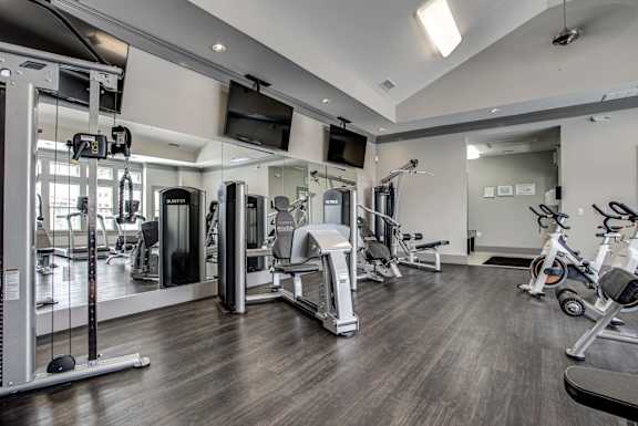 A spacious gym with a variety of equipment including treadmills, stationary bikes, and weight machines. at River Crossing Apartments, St. Charles, Missouri