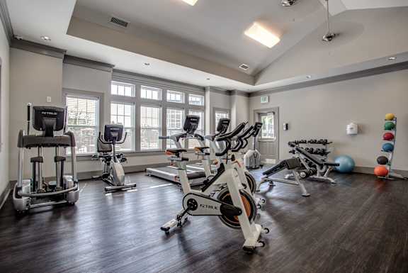 A gym with a variety of exercise equipment including treadmills, stationary bikes, and weight machines. at River Crossing Apartments, Missouri, 63303