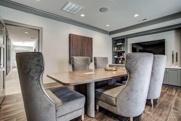 A modern dining room with a wooden table and grey chairs. at River Crossing Apartments, Missouri