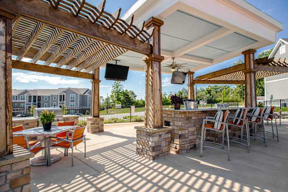 A patio with a table and chairs under a roof. at River Crossing Apartments, St. Charles, 63303