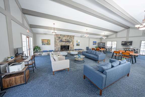 A spacious living room with a fireplace and a variety of seating options at Rivers Edge Apartments, Michigan, 48327